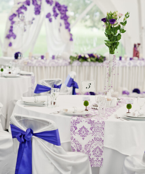 Beautiful wedding set decoration in the restaurant. Chairs with violet ribbons.